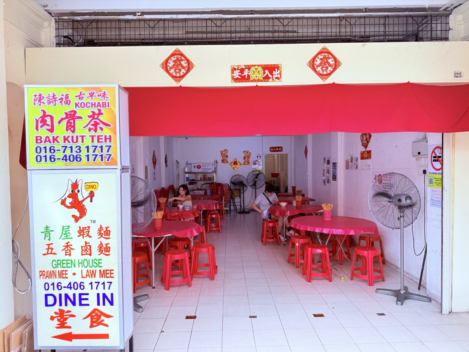 The no-frills dine-in unit with red round tables, red plastic stools, standing fans and a Dine In arrow sign